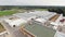 Drone camera shows roofs of modern clean fenced farm with pile of round bales.