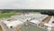 Drone camera shows roofs of modern clean fenced farm with square cows paddocks