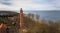 A drone captures Gaski beach, West Pomeranian Voivodeship, Poland, featuring a red brick lighthouse, Baltic Sea, sandy shore,