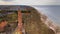 A drone captures Gaski beach, West Pomeranian Voivodeship, Poland, featuring a red brick lighthouse, Baltic Sea, sandy shore,