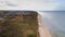 A drone captures Gaski beach, West Pomeranian Voivodeship, Poland, featuring a red brick lighthouse, Baltic Sea, sandy shore,