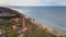 A drone captures Gaski beach, West Pomeranian Voivodeship, Poland, featuring a red brick lighthouse, Baltic Sea, sandy shore,