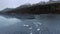 Drone circles over a trumpeter swan herd, swans play in the water at Summit Lake, Alaska, USA