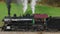 Drone Close Up View of a Steam Locomotive Stopped Wait for a Train to Pass, Blowing Smoke