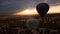 Drone closeup view of hot air balloon flying in the sky over volcanic hills against amazing sunset