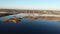 Drone descends over the estuary of a river. On the bank there are dry reeds.