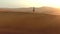 Drone, desert and man walking on dune landscape, sunshine and nature for adventure in summer. Sunset, horizon and sand