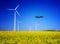Drone on a field with windmills. Rapeseed field in bloom. Renewable energy. Protect the environment