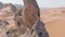 A drone flies around a bearded man dressed as a shaman who prays on a cliff in the sandy desert of the United Arab