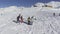 Drone flies circles over skiers and snowboarders on winter snow covered hill top