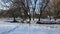 The drone flies low above the ground towards the river. Winter park, human footprints in the snow. Aerial video filming of the