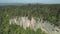 Drone flies near mixed deep forest with high firsor spruce. Beautiful summer landscape with valleys, trees crowns