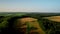 Drone flies in orbit around the golden field with sunrise over the forest and meadow