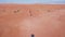 A drone flies over a caravan of buggies driving through the desert sand