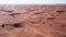 A drone flies over a caravan of buggies driving through the desert sand