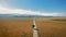 Drone flies over a long, straight road that runs across the wide prairie to the horizon near Mormon Row, Wyoming