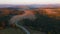 Drone flies over a road that runs through a coniferous forest in light of sunset. Filmed in 4k, drone video