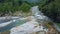 Drone flies over rocky bank river tourists stand on stones