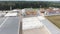 Drone flies over roofs of modern clean fenced farm with pile of round bales.