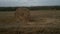 The drone flies past the haystacks and opens a panorama of the harvested field.