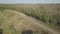 Drone flight along a dirt rural road next to an agricultural field