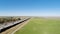 Drone Flight Over Grass Field With Blue Sky Near Freeway