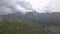 Drone flight over a high alpine mountain road pass. The drone fly`s over the barren mountain terrain. The clouds form over the bac