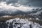 drone flight over snowy mountain range, with dramatic storm clouds in the background