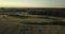 Drone flight at sunset over wheat field and golf court with city in background