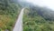 Drone flying above foggy winding mountain road near misty rainforest trees. Cinematic footage aerial view  majestic tropical mount