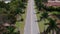 Drone flying above shot of road lined with tall palm trees.