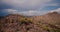 Drone flying around large stone hill with lone cactus on top in amazing stormy desert at Arizona national park reserve.