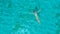 DRONE: Flying away from Caucasian woman swimming on her back by the exotic beach