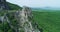 A drone flying from a bird\'s eye view of a mountain with bare rocks  surrounded by green trees vegetation