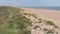 Drone flying from bushes over the sand beach towards the sea in united kingdom