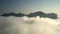 Drone flying. Fascinating mountain range appears because slowly dispersing fog