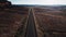 Drone flying forward over straight desert highway road in USA wilderness near massive rocky mountain and beautiful sky.