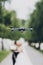 Drone flying in green part. Drone photo and footage of wedding day concept. Black drone on background of blurred wedding couple in