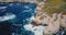 Drone flying high above beautiful ocean shore, foaming waves crash over large rocks at summer Big Sur scenery California