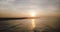 Drone flying high over incredible ocean surface reflecting sunset and waves reaching coast line. Paradise beach view.