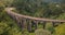 Drone flying left and turning to reveal magnificent wide panoramic aerial view of Nine Arch Bridge Ella in Sri Lanka.