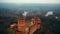 Drone flying low over ancient Turaida castle and museum reserve in Sigulda, Latvia, autumn foggy forest and river view.