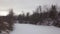 Drone is flying low over frozen snowy river in forest in winter day