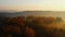 Drone flying over epic autumn forest and lake, trees are covered with foggy mist. Amaing peaceful sunset nature.