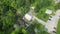 Drone flying over rural houses with trees and parked cars on a highland with waterfall