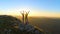 DRONE: Flying over sporty couple outstretching arms after a successful hike.