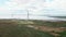 Drone flying straight on wind turbine cloudy sky and lake on background