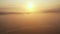 Drone flying through thick fog over mysterious field and winding river, rising to reveal epic rising sun valley panorama