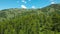 DRONE: Flying towards the towering rocky mountains and over a vast pine forest.