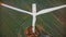 Drone flying very close up to working windmill turbine with red stripes, alternative ecological energy sources concept.